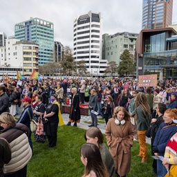 A large crowd of people gathered in an urban plaza.