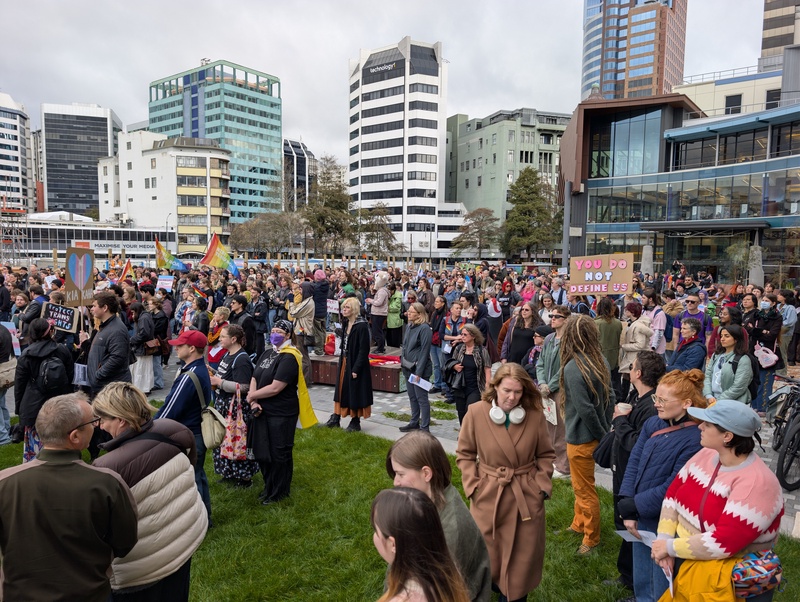 A large crowd of people gathered in an urban plaza.