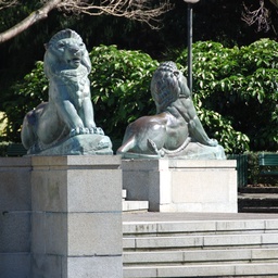 Two bronze lion statues on pedestals in a park set