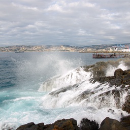 Ocean waves crashing against dark rocks on a coastline.