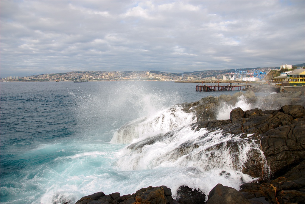Ocean waves crashing against dark rocks on a coastline.