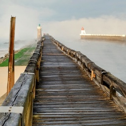 A weathered wooden pier extends into fog