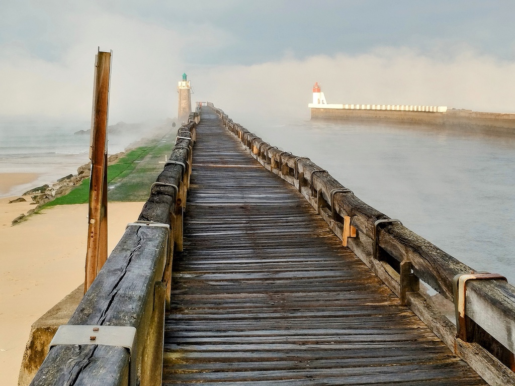A weathered wooden pier extends into fog