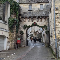 A cobblestone street leads through an old stone wall