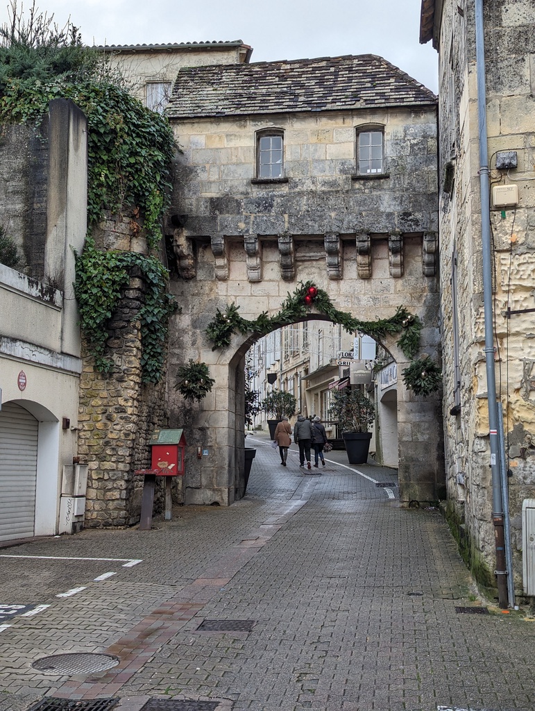 A cobblestone street leads through an old stone wall