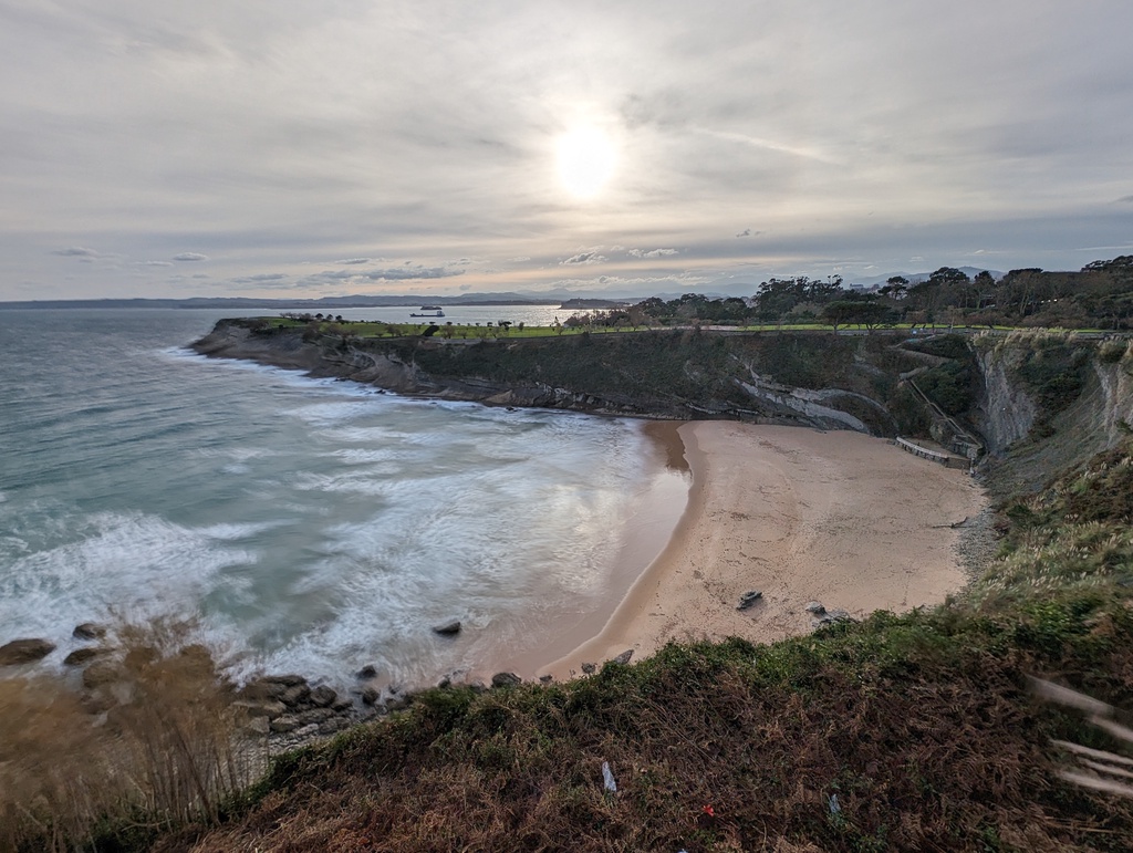 A coastal landscape with a sandy beach, crashing w