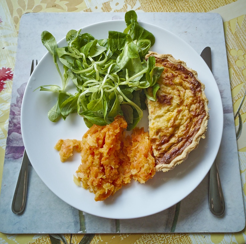 A plate of quiche and salad with mashed carrot & parsnip.
