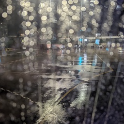 An out-of-focus, wet asphalt road at night.