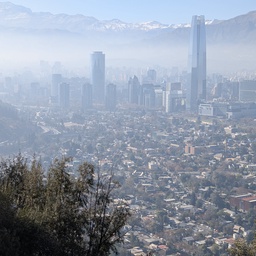 A hazy, mountain-backed cityscape with tall skyscrapers.