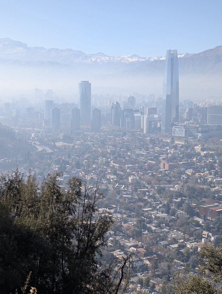 A hazy, mountain-backed cityscape with tall skyscrapers.
