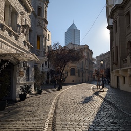 A cobblestone street in a city with tall buildings and a skyscraper in the background.