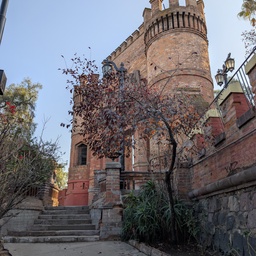 A brick castle tower rising above a garden path.