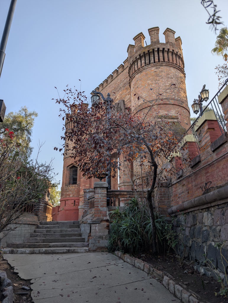A brick castle tower rising above a garden path.