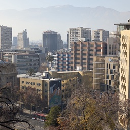 A cityscape of high-rise buildings set against a mountain range.