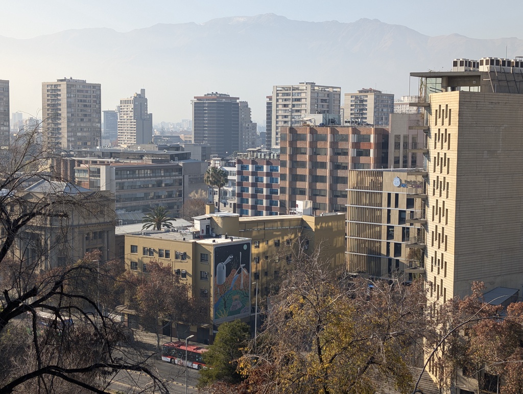 A cityscape of high-rise buildings set against a mountain range.