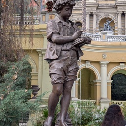 A bronze statue of a young boy holding a book.