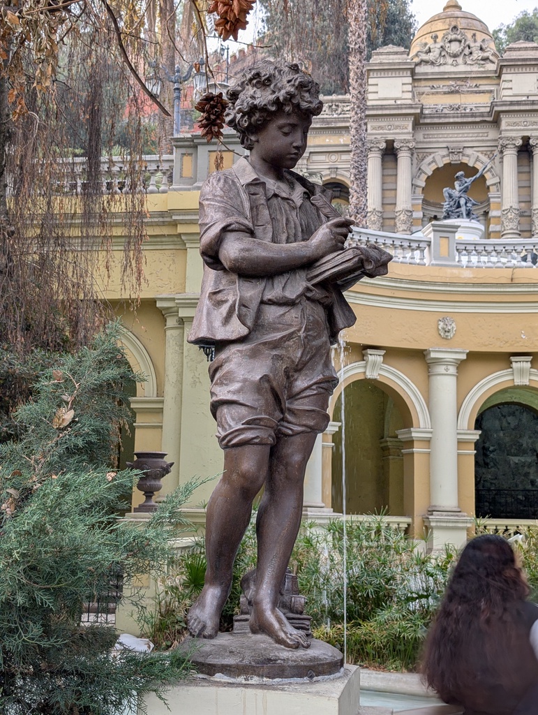 A bronze statue of a young boy holding a book.