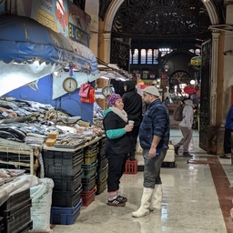 An indoor market stall with fish and people browsing.