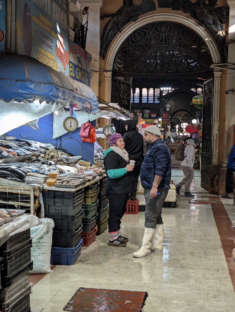 An indoor market stall with fish and people browsing.