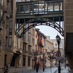 An elevated glass bridge connecting two buildings in a city street.