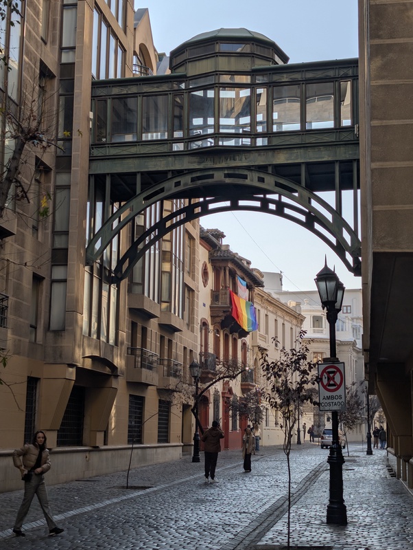 An elevated glass bridge connecting two buildings in a city street.