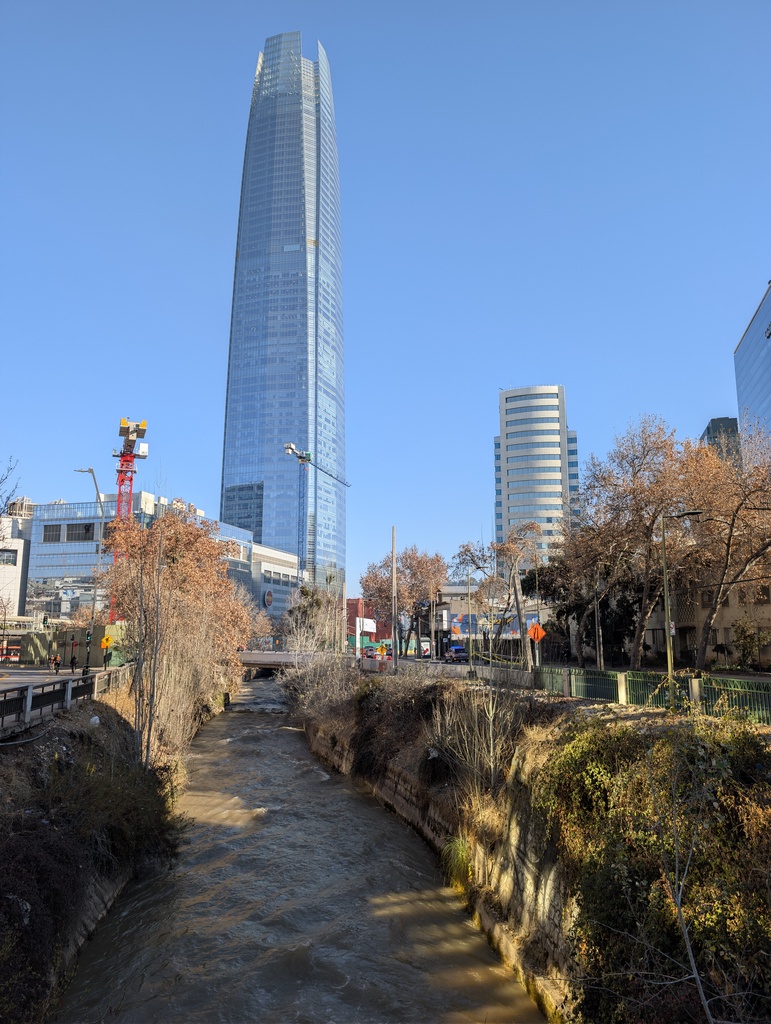 A tall, blue glass skyscraper in a city landscape.