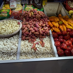 An assortment of various nuts, seeds, and colorful vegetables in a market stall.