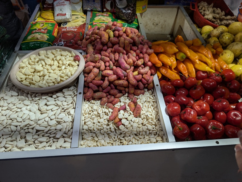 An assortment of various nuts, seeds, and colorful vegetables in a market stall.