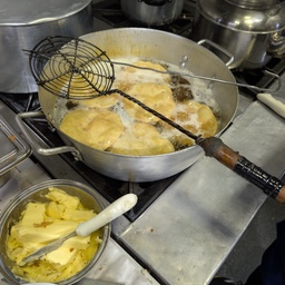 Flatbreads being fried in a large pan of oil.