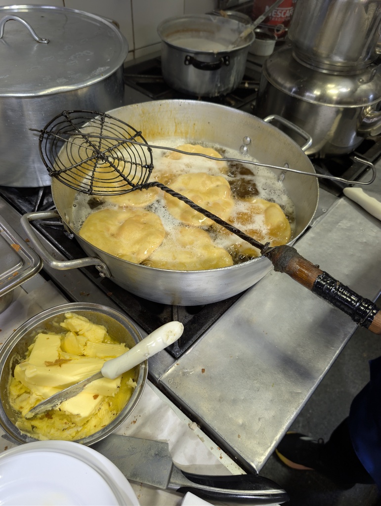 Flatbreads being fried in a large pan of oil.
