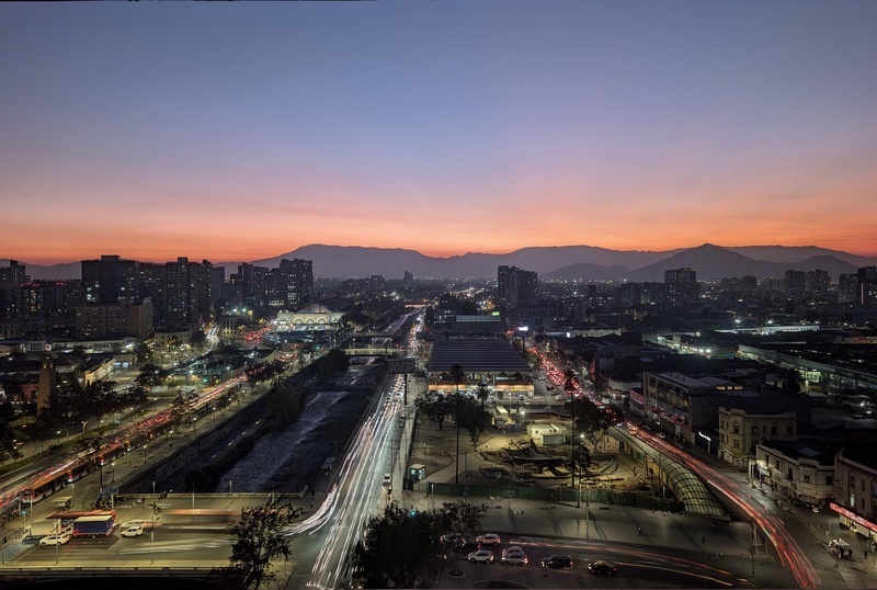 An orange sunset over a city skyline with mountains in the distance.