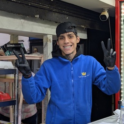 A smiling young man in a blue fleece jacket standing behind a counter.