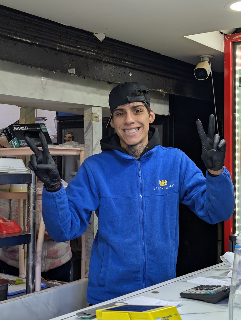 A smiling young man in a blue fleece jacket standing behind a counter.