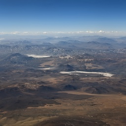 An aerial view of a vast, mountainous desert landscape.