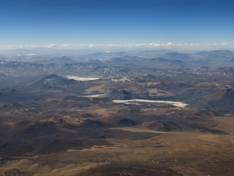 An aerial view of a vast, mountainous desert landscape.