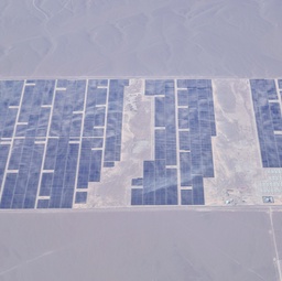 An aerial view of a large solar farm in a desert landscape.