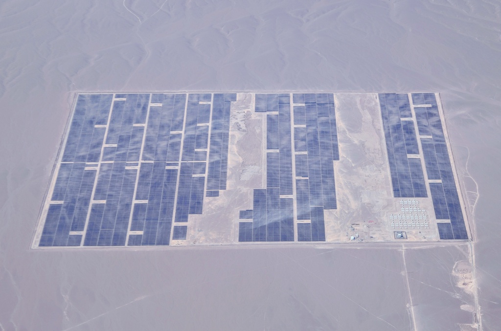 An aerial view of a large solar farm in a desert landscape.