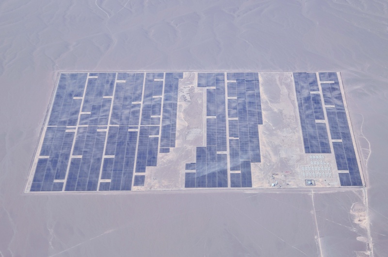 An aerial view of a large solar farm in a desert landscape.