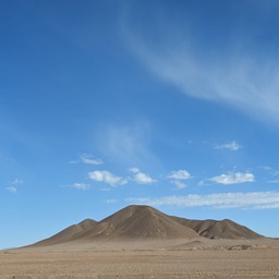 A lone desert mountain under a bright blue sky.